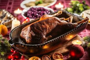 Weihnachten braten Gans mit rot Kohl, Kartoffel Knödel im ein Original Backen Gericht auf das festlich Tabelle foto
