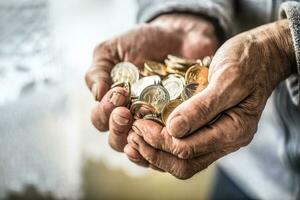 Rentner Mann halten im Hände Euro Münzen. Thema von niedrig Renten foto