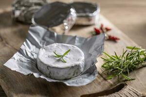 Alufolie Pakete von Brie Käse mit Rosmarin und Chili auf ein Schneiden Tafel foto