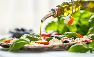 Gießen Olive Öl auf Caprese Salat. gesund Italienisch oder Mittelmeer Mahlzeit foto