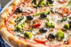 irtalisch Pizza mit Brokkoli Spinat Tomaten Oliven und Mozzarela oder Parmesan Käse. Mittelmeer Vegetarier Mahlzeit foto