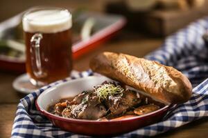 braten wild Eber mit Karotte Pilze, Stangenbrot und Entwurf Bier foto