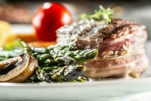 gegrillt Steak serviert auf ein Teller mit Spargel, Kartoffeln und Tomate foto