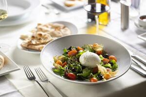 Italienisch Salat mit Ball von Büffel Mozzarella im das Mitte serviert im ein Teller mit ein Fladenbrot und rot Wein foto