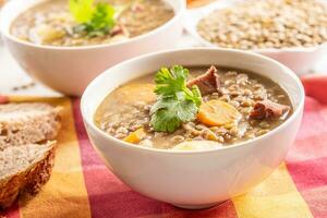 Linse Suppe mit Stücke von geräuchert Schweinefleisch Nacken, Möhren, Kartoffeln und Koriander foto