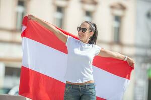 jung Frau draußen hält ein Flagge von Österreich, lächelnd foto