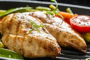 Nahansicht von gegrillt Hähnchen Brüste auf ein schwenken mit frisch Grün Gemüse und Kirsche Tomaten und Rosmarin foto