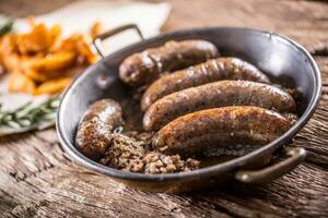 Würstchen.gebraten Schweinefleisch Würstchen im ein schwenken mit Kartoffeln und Rosmarin foto