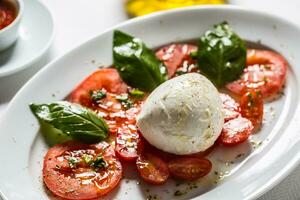 Caprese Salat von Mozzarella Tomaten Basilikum Olive Öl ein Gewürze foto