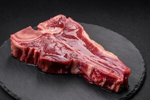 roh frisch saftig Rindfleisch T-Bone Steak mit Salz, Gewürze und Kräuter foto