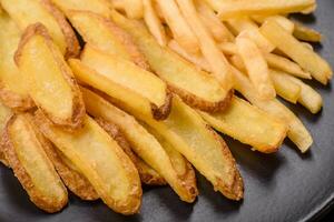 köstlich knusprig Französisch Fritten mit Salz- und Gewürze auf ein texturiert Beton Hintergrund foto