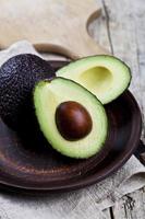 Frische Bio-Avocado auf Keramikplatte und Leinenserviette auf rustikalem Holztischhintergrund. foto