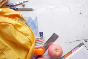 zurück zum Schulkonzept mit gelbem Rucksack und Schulmaterial auf dem Tisch foto