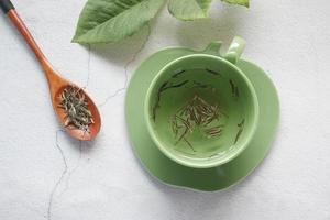 Draufsicht auf grünen Tee und Kräuterblatt in einer kleinen Glasschale foto