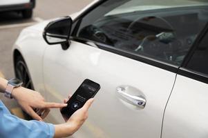 Hand mit Telefon zum Entsperren des Autos aus nächster Nähe foto