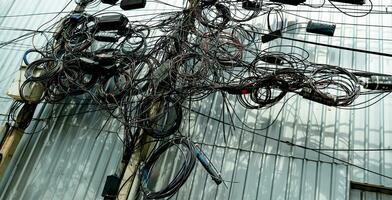 verheddert elektrisch Drähte und verheddert Kommunikation Linien auf städtisch elektrisch Stangen erstellen ein chaotisch Netzwerk. unorganisiert und unordentlich zu Organisation Verwaltung Konzept. sollte nehmen unter Tage Kabel. foto