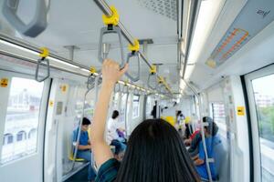 Frau Hand Feste Griff Sicherheit Geländer im erhöht Einschienenbahn Zug. Masse Transit System im modern Stadt. Innerhalb von elektrisch Zug. Tourist Reise durch Stadt Himmel Zug. Öffentlichkeit Transport. städtisch Transport. foto