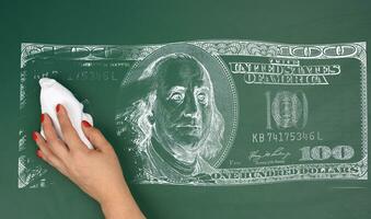 Kreide drucken von ein einer Hundert-Dollar Rechnung auf ein Grün Tafel und ein weiblich Hand abwischen aus das drucken, Konzept von Inflation foto