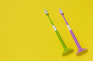 zwei Plastik Zahnbürsten auf ein Gelb Hintergrund, Oral Hygiene foto