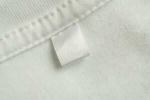 leer Weiß Wäsche Pflege Kleider Etikette auf Weiß Hemd Stoff Textur Hintergrund foto