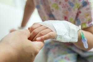 Mutter halten Kind Hand mit Kochsalzlösung iv Lösung im Krankenhaus foto