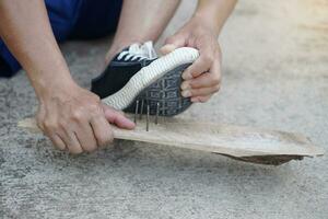 schließen oben Hände sind ziehen aus Nägel von Schuhe. Konzept, unsicher , Risiko zum gefährlich Tetanus. Sein Vorsichtig und aussehen um während Gehen auf das Fußboden oder Risiko setzt. Unfall foto