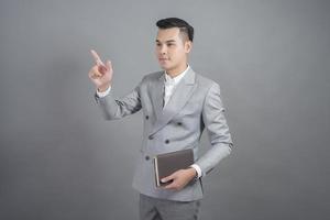 Geschäftsmann berührt virtuellen Bildschirm, Porträt im Studio grauen Hintergrund foto