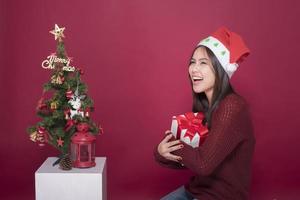 schönes Weihnachtsmann-Mädchen im Studio auf rotem Hintergrund, Weihnachtskonzept