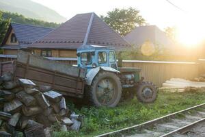 russischer alter traktor im dorf in den bergen mit sommersonnenuntergang foto