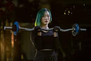 asiatisch Frau ist trainieren Gewicht Leben mit einfach Bar wie Anfänger auf Hantel zum Arm und Ader Muskel Innerhalb Fitnessstudio mit dunkel Hintergrund zum ausüben und trainieren Konzept foto