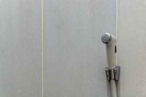 Weiß Bidet Dusche hängend auf das Weiß Keramik Mauer. Toilette Dusche zum Waschen extern Genital. foto