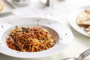 Spaghetti mit gehackt Fleisch gemacht im ein Bolognese Stil serviert im ein Teller mit bestreut frisch Kräuter foto