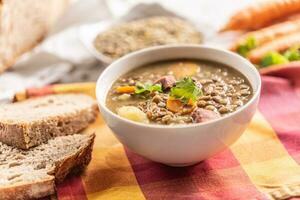 Linse Suppe mit Stücke von geräuchert Schweinefleisch Nacken, Möhren, Kartoffeln und Koriander foto