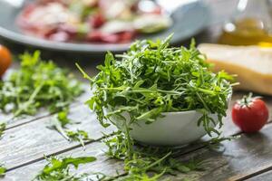frisch Rucola Salat im Weiß Gericht auf hölzern Tabelle foto