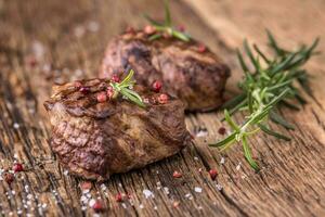 gegrillt Rindfleisch Steak mit Rosmarin, Salz- und Pfeffer auf alt Schneiden Tafel. Rindfleisch Filet Steak. foto