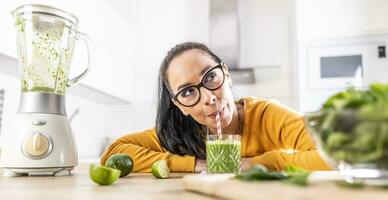 ein komisch jung Frau Getränke ein Grün Smoothie Das sie gemacht Sie selber foto