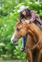 gut suchen Mädchen lacht und Streicheleinheiten das braun Pferd während ein Sommer- Reiten im das Natur foto
