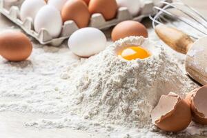 Detail von Teig Vorbereitung mit Ei Eigelb, Mehl, Eier, rollen und ein Schneebesen auf ein Tabelle foto