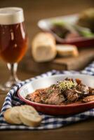 braten wild Eber mit Karotte Pilze, Stangenbrot und Entwurf Bier foto