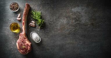 roh Tomahawk Steak mit Salz- Gewürze Knoblauch und Kräuter auf ein alt rustikal Tafel - - oben von Aussicht foto