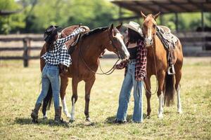 Frauen satteln oben ihr Pferde auf ein Ranch Vor Reiten Sie foto