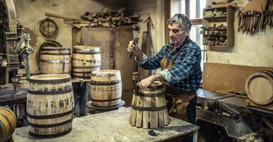 alt Mann Kunsthandwerk ein Neu Vintage-Look hölzern Fass mit Hammer zu stellen das Metall Ring um das Stücke von Holz foto