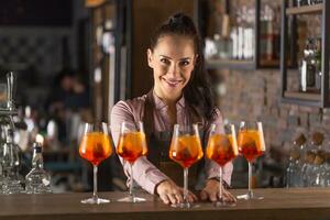 schön Barmann dient fünf Orange Cocktails im Wein Brille auf ein Bar foto