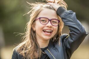 Porträt von ein glücklich lächelnd Teenager Mädchen mit Dental Hosenträger und Brille foto