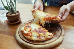 ein Scheibe von frisch heiß sehr käsig Vegetarier Pizza Mozzarella Käse. Italienisch Pizza Margherita im Hand foto