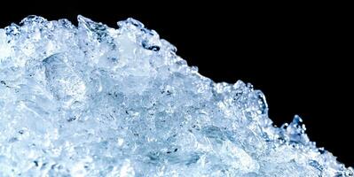 Haufen zerkleinerter Eiswürfel auf dunklem Hintergrund mit Kopierraum. Crushed Ice Cubes Vordergrund für Getränke. foto