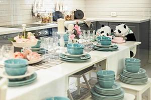 zwei Pandas sitzen am Tisch zwischen dem Geschirr