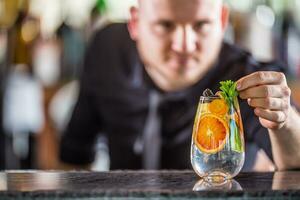 Fachmann Barmann dekorieren Gin Tonic Cocktail trinken und dekoriert es mit Minze Kräuter foto