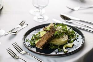 luxuriös Tabelle Rahmen mit ein dunkel Teller voll von Vegetarier Salat mit mariniert Tofu foto