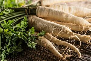 Nahansicht Pastinake mit Petersilie oben auf hölzern Tafel foto